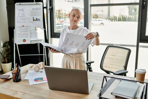 In an elegant office, a young bald woman analyzes reports, surrounded by charts and papers. — Stock Photo