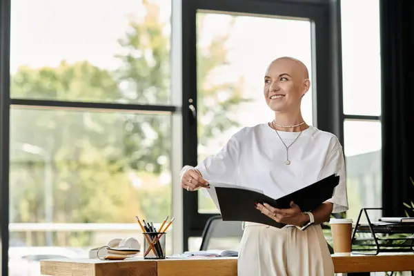 Una giovane donna sicura di sé con una testa calva sorride mentre organizza la sua cartella in un ufficio. — Foto stock