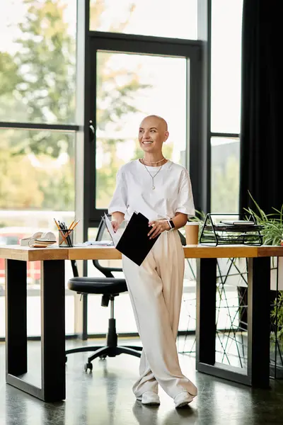 A young bald woman stands gracefully in an office, showcasing her elegant outfit and vibrant smile. — Stockfoto