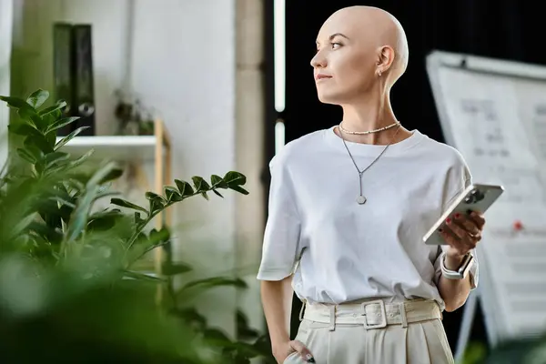 A young bald woman wearing chic attire stands gracefully among lush plants, engaging thoughtfully. — Stock Photo