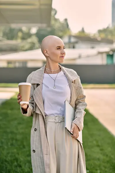 Dressed in stylish clothing, a bald woman strolls leisurely, sipping coffee and carrying a notebook. — Stock Photo