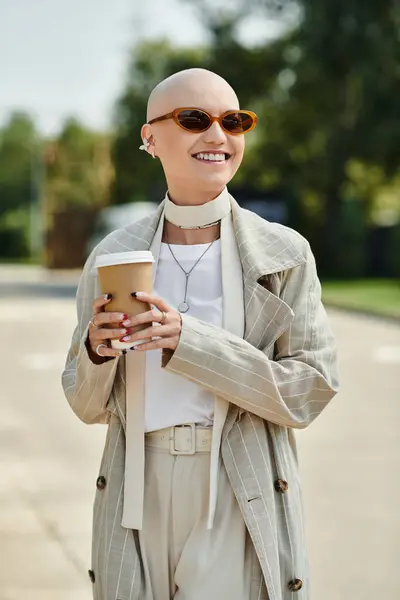 A young bald woman radiates confidence in elegant attire while holding coffee outdoors. — Stock Photo