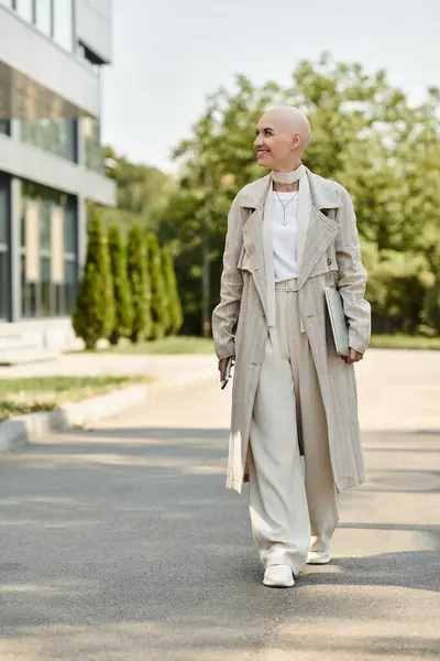 A confident young woman in chic attire strolls through a sunny outdoor setting, exuding grace. — Stock Photo