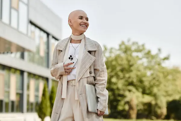 Dressed in an elegant outfit, a bald woman beams with joy while holding her phone outside. — Stock Photo