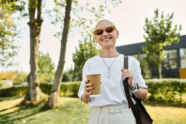 A confident young woman in elegant attire enjoys her coffee, smiling warmly under the sun. — Stock Photo