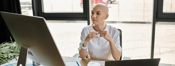 Uma jovem careca em roupas elegantes senta-se em sua mesa, profundamente contemplada, envolvida no trabalho. — Fotografia de Stock