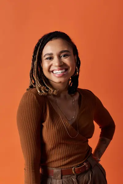 A young, stylish woman with braided hair conveys joy while posing against a bright background, showcasing confidence. — Stock Photo
