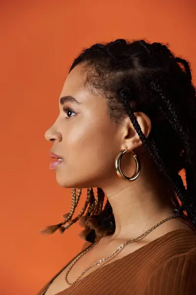 A young African American woman with beautiful braids showcases her style in a vibrant studio setting. — Stock Photo