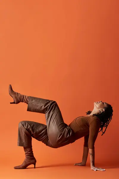 Una joven con el pelo trenzado muestra su atuendo elegante mientras posa creativamente en un estudio brillante. — Stock Photo