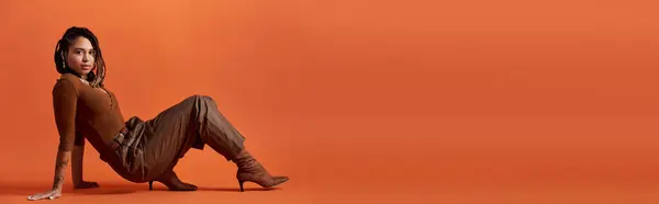 Uma jovem mulher com cabelo trançado faz uma pose elegante em um cenário de estúdio dinâmico, mostrando seu estilo. — Fotografia de Stock