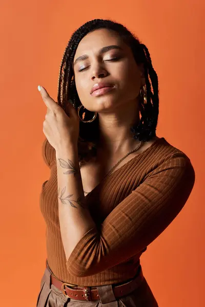 A young African American woman with braided hair strikes a stylish pose, reflecting confidence and creativity. — Stock Photo