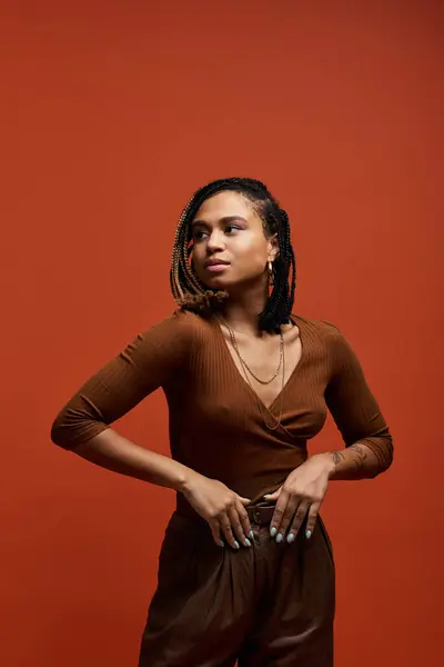 A fashionable young African American woman with braided hair stands in a studio, showcasing her unique style. — Stock Photo
