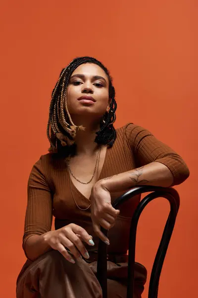 A young African American woman showcases her unique style in a striking studio space with an orange backdrop. — Stock Photo