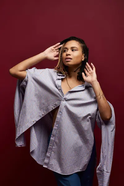 Une jeune femme afro-américaine aux cheveux tressés tendance pose audacieuse sur fond vibrant. — Photo de stock