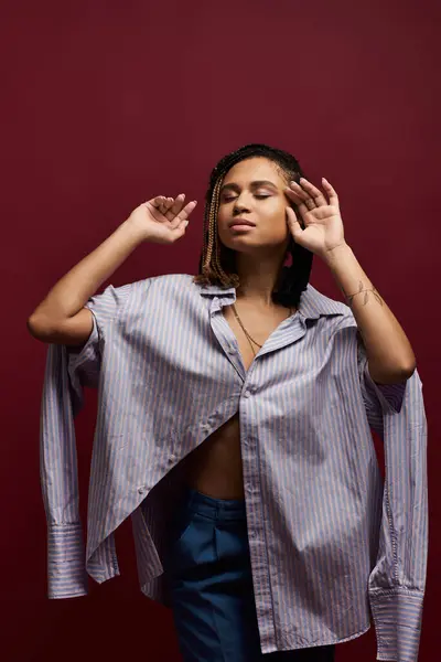 A stylish young Black woman with braids confidently poses in a vibrant studio, celebrating her individuality. — Stock Photo