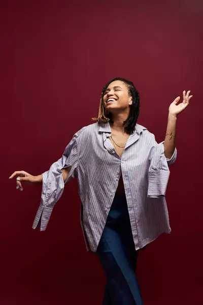 A young African American woman with braided hair exudes confidence while posing in a vibrant studio backdrop. — Stock Photo