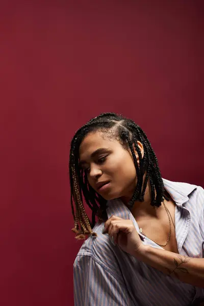 A young African American woman showcases her trendy braided hairstyle in a vibrant studio atmosphere. — Stock Photo