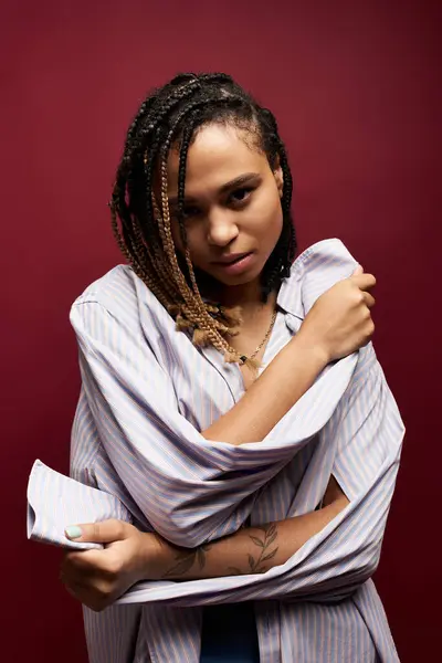 A young woman with beautiful braids embraces her style, showcasing confidence in a striking studio backdrop. — Stock Photo