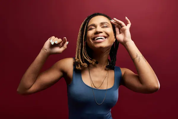 A stylish African American woman with braided hair is joyfully posing in a vibrant studio environment. — Stock Photo