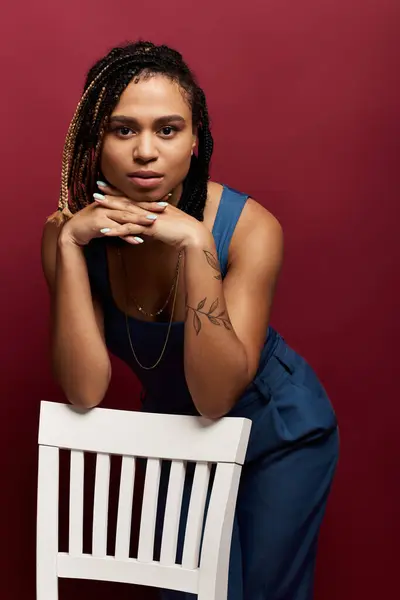 A young African American woman with braided hair strikes a confident pose in a stylish studio setting. — Stock Photo