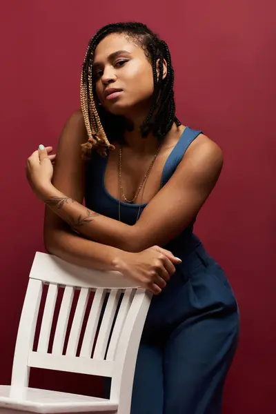 A confident young woman showcases her braided hairstyle while posing elegantly against a vibrant background. — Stock Photo