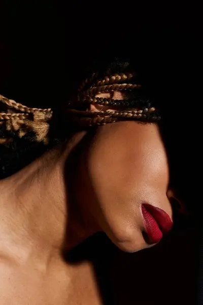 Une jeune afro-américaine pose gracieusement dans un studio, mettant en valeur ses cheveux tressés et ses lèvres rouges frappantes. — Photo de stock