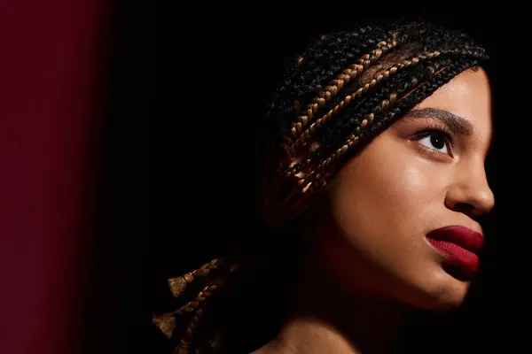 A young, fashionable woman with braided hair showcases her confident style while striking a pose in the studio. — Stock Photo