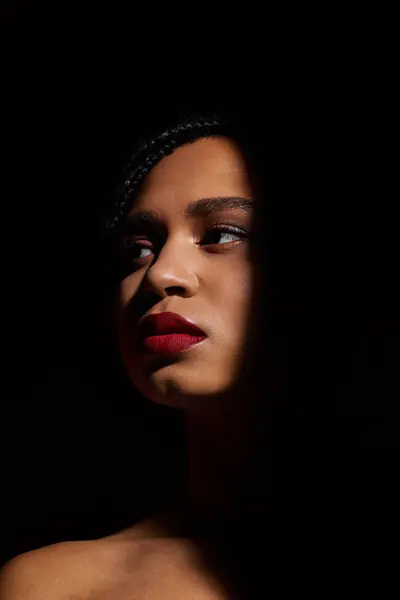 A young African American woman with braided hair and striking red lips showcases a confident pose in a studio. — Stock Photo