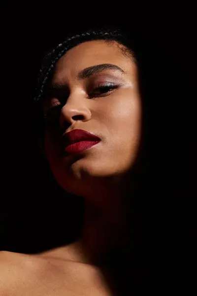 A fashionable young woman confidently poses with braided hair and striking red lips in a studio atmosphere. — Stock Photo