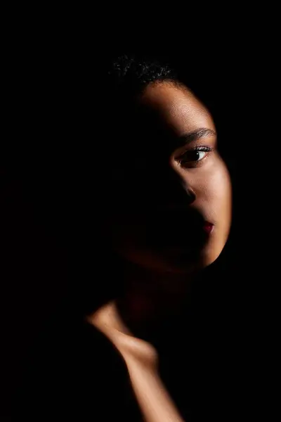 A fashion-forward young woman showcases her style against a dark, dramatic backdrop. — Stock Photo