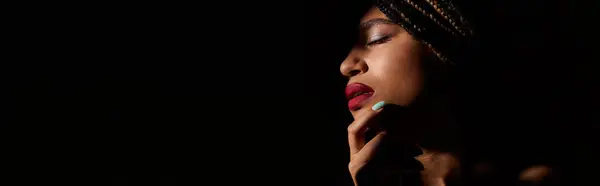 A young African American woman with braided hair showcases her bold red lips and striking pose in a studio. — Stock Photo