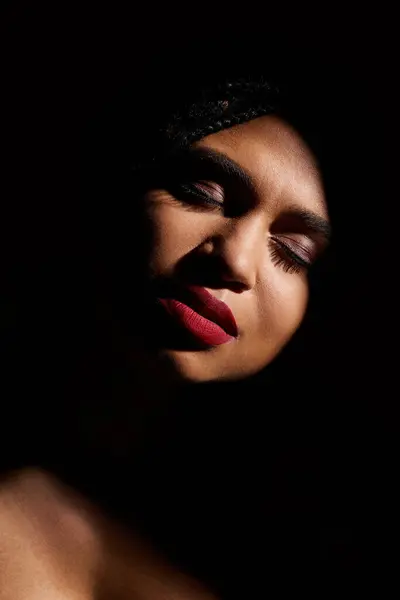 Uma mulher afro-americana elegante com lábios vermelhos ousados contra um pano de fundo escuro. — Fotografia de Stock