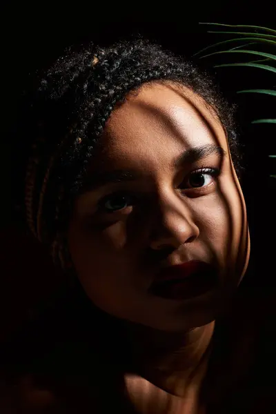 Une jeune afro-américaine aux cheveux tressés met en valeur son style et sa confiance dans une mise en scène dramatique en studio. — Photo de stock