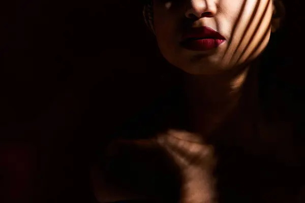 A young African American woman in a studio showcases her vibrant red lips with confidence. — Stock Photo