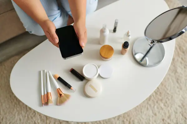 A young woman taking photo of beauty products while relaxing in a stylish living room atmosphere. — Stock Photo