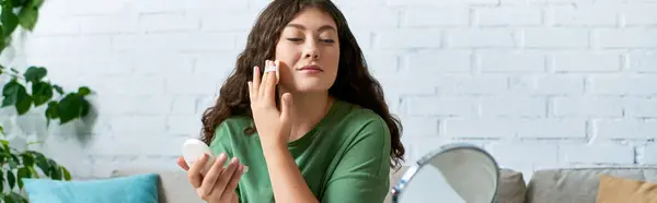Una giovane donna dai capelli ricci applica il trucco mentre è circondata da prodotti di bellezza nel suo soggiorno. — Foto stock