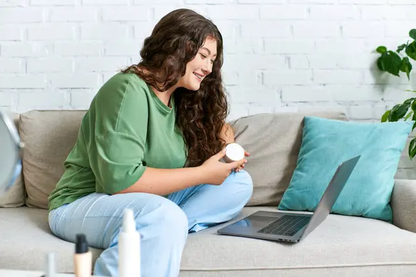 A cheerful woman with curly hair relaxes on the couch while exploring her beauty routine with cosmetics. — Stock Photo