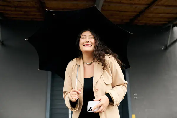 A cheerful plus size woman embraces the autumn weather with a smile while holding an umbrella outside. — Stock Photo
