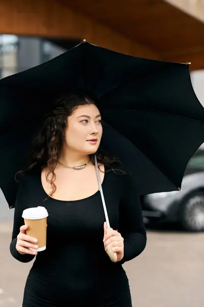 A beautiful plus size woman is walking outside on a crisp autumn day, sipping coffee and carrying an umbrella. — Stock Photo