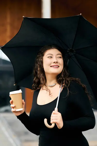 Уверенная женщина plus-size с кудрявыми волосами поглаживается по улице, держа в руках чашку кофе и черную пумбрию.. — Stock Photo