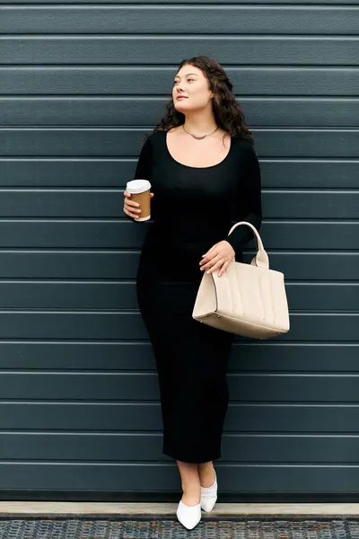 A beautiful plus size woman enjoys a breezy autumn day, gracefully walking outdoors in her stylish black dress. — Stock Photo