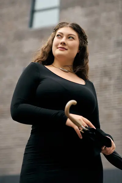 A plus size woman strolls gracefully in a black dress, embracing the beauty of autumn outdoors. — Stock Photo