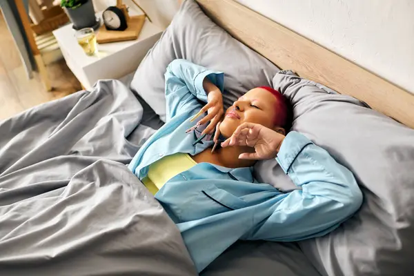 A young woman stretches comfortably in her bed, embracing the tranquility of the morning. — Stock Photo