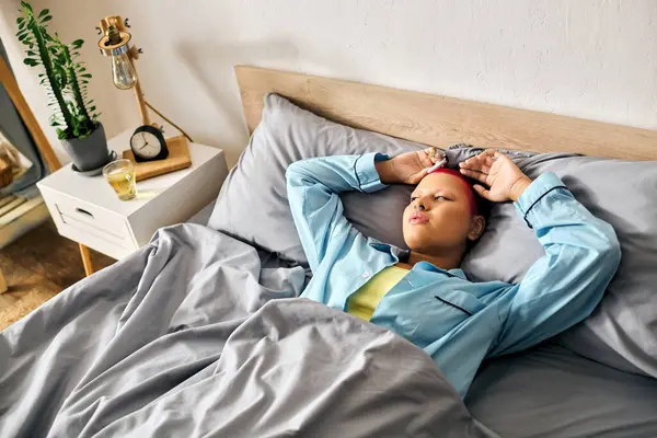 A young woman lies comfortably in bed, enjoying a serene morning at home. — Stock Photo