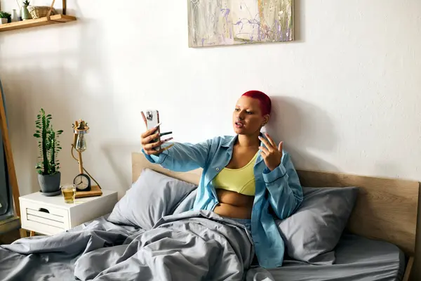 Relaxing in bed, a young woman captures a fun selfie in her cozy bedroom. — Stock Photo