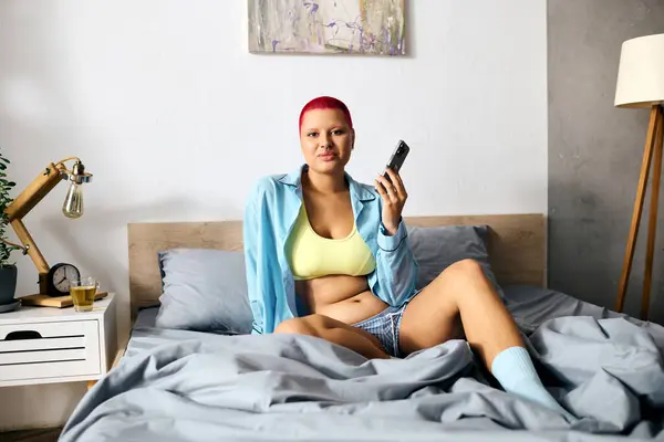 A young woman sits comfortably in bed, engaged with her device and enjoying her time at home. — Stock Photo