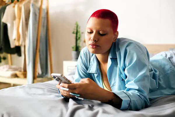 Eine junge Frau entspannt sich im Bett, blättert durch ihr Smartphone und genießt ihre Zeit. — Stockfoto