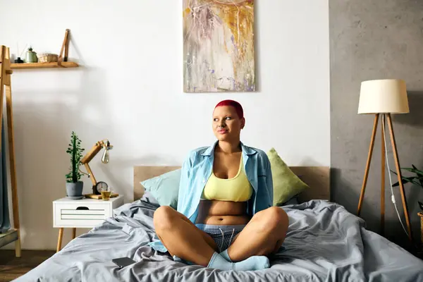 A young woman sits comfortably on her bed, embracing a relaxed moment at home. — Stock Photo
