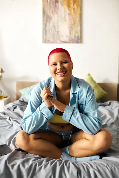A cheerful young woman with vibrant hair relaxes on her bed, radiating joy in her cozy space. — Stock Photo