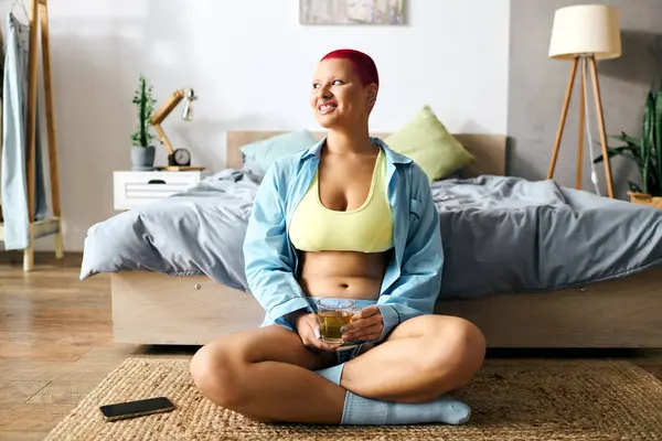 In a vibrant room, a young woman sits cross legged, radiating joy while sipping her drink. — Stock Photo